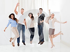Confident businesspeople jumping with arms raised