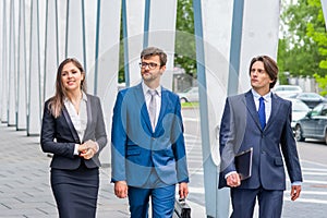 Confident businesspersons talking in front of modern office building. Businessmen and businesswoman have business