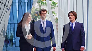 Confident businesspersons talking in front of modern office building. Businessmen and businesswoman have business