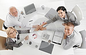 Confident businessteam holding hands at meeting