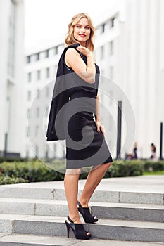 Confident businesswoman in black clothes smiling and looking at camera