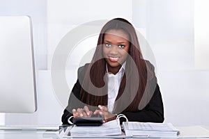 Confident businesswoman calculating tax at desk