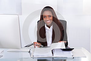 Confident businesswoman calculating tax at desk