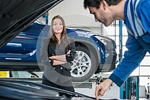 Confident Businesswoman With Mechanic Repairing Her Car