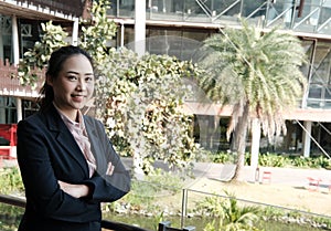 confident businesswoman standing with arms crossed outside office building. young female entrepreneur woman smiling outdoors.