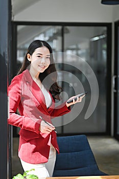 Confident businesswoman standing in office and smiling too camera.