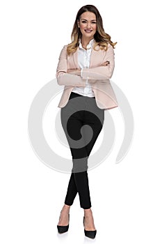 Confident businesswoman stands with arms folded and legs crossed