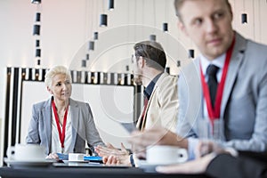 Confident businesswoman talking to businessman in convention center