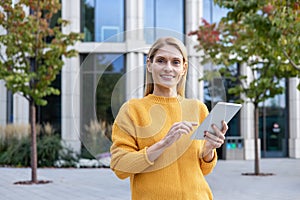 Confident businesswoman using tablet outside modern office