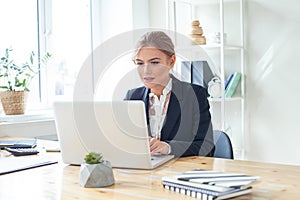 Confident businesswoman working on laptop at her workplace at modern office