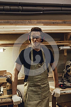 Confident carpenter standing near workbenches