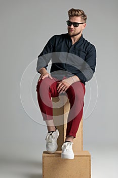 Confident casual man sitting on a throne made of boxes