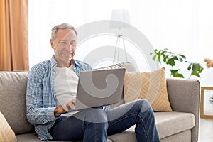 Confident casual mature using laptop at home