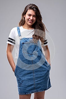 Confident casual young woman in a denim pinafore