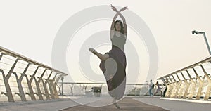 Confident Caucasian ballerina raising up leg in slow motion. Wide shot portrait of charming young woman dancing ballet