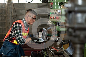 A Confident Caucasian technician engineer use laptop to maintenance and control machines in workplace on a business day