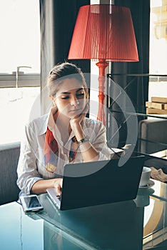 Confident caucasian young woman working on laptop in modern cafe