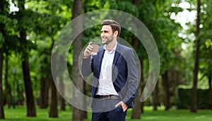 Confident CEO with takeout coffee enjoying his morning walk at urban park