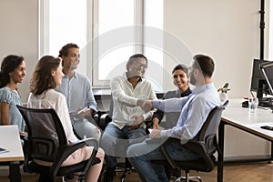 Confident cheerful Indian and Caucasian business colleagues shaking hands