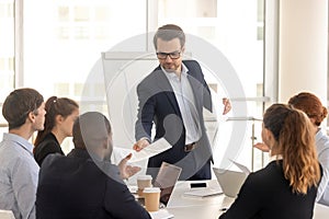 Confident coach giving handout to diverse seminar participants photo