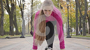 Confident concentrated Caucasian woman looking up and starting running. Attractive female runner training in the morning