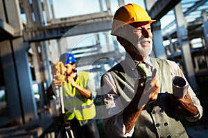 Confident construction engineer, architect, businessman in hardhat working on building site