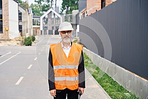 Confident construction superintendent with walkie-talkie posing outdoors