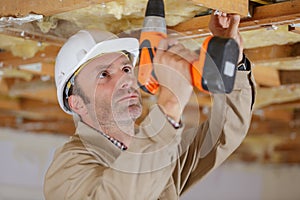 confident constructor carpenter or builder man working wood drill