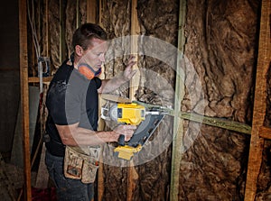 Confident constructor carpenter or builder man working wood with electric drill at industrial construction site in installation a