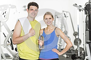 Confident Couple With Towel And Water Bottle In Gym