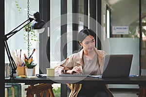Confident creative asian woman working with laptop computer in office