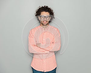 confident curly hair man with glasses smiling and crossing arms