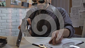 Confident detective charging gun sitting in police station, protection and order