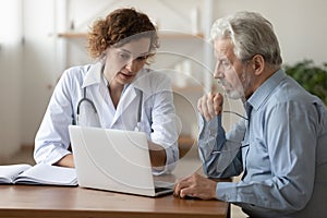 Confident doctor consulting mature patient at medical appointment