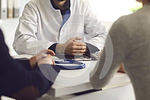 Confident doctor and couple patient sitting at the table in clinic office. Family doctor.