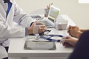 Confident doctor and couple patient sitting at the table in clinic office. Family doctor.