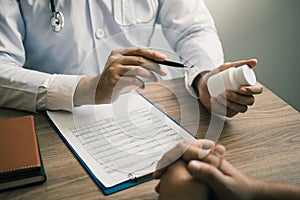 Confident doctor man holding a pill bottle and talking with senior patient and reviewing his medication at office room