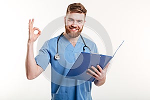 Confident doctor or nurse with clipboard in hand showing okay gesture