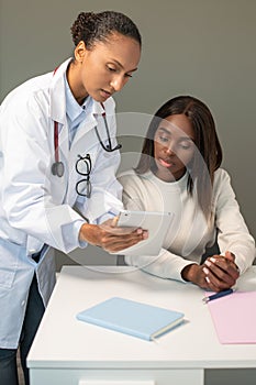 Confident doctor showing medical tests on touchpad to woman