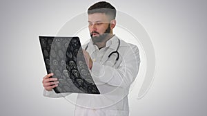 Confident doctor working with MRI scan results on gradient background.