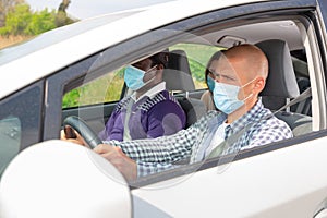 Confident driver in protective mask driving car with passengers