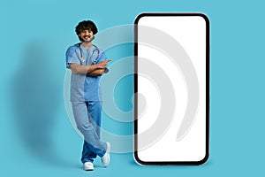 Confident eastern doctor pointing at huge phone with white screen