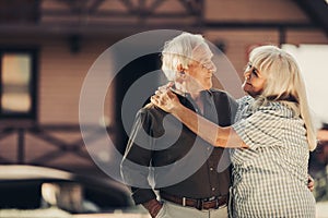 Confident elderly couple standing in front of home