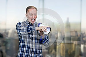 Confident elderly mature man giving a speech in megaphone and pointing at something.