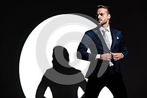 confident elegant man looking to side and closing navy blue suit