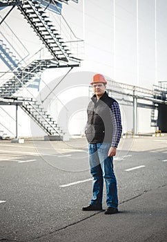 Confident engineer posing against warehouse