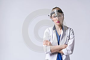 Confident ENT doctor wearing surgical headlight head light and protective glasses. Portrait of female otolaryngologist