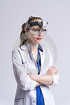 Confident ENT doctor wearing surgical headlight head light and protective glasses. Portrait of female otolaryngologist