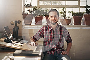 Confident entrepreneur designer sitting in his office space