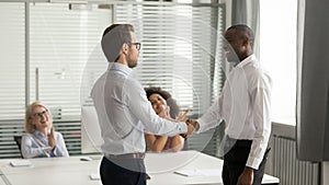 Confident executive shaking hand of successful African American employee